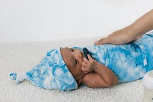 Anonymous mother with newborn baby wrapped on soft blanket with pacifier photo