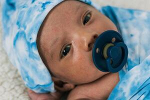 Newborn baby wrapped on soft blanket with pacifier photo