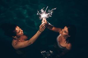 Cheerful friends burning sparkles near pool photo