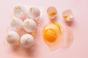 Festive Easter eggs in box and broken egg on table photo