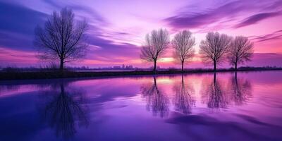A purple sunset with trees reflected in the water photo