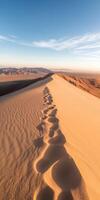 Footprints in the sand of a desert dune photo