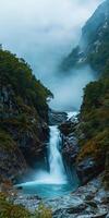 A waterfall in the mountains with fog and trees photo
