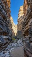 A narrow canyon in the desert with rocks and dirt photo