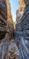 A narrow canyon in the desert with rocks and water photo