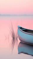 A canoe sits on the water in a pink sky photo