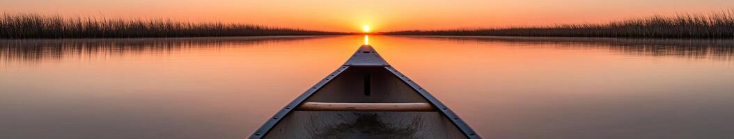 A canoe is seen in the middle of a lake at sunset photo
