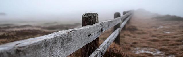 A fence is shown in the fog on a hill photo