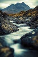 A river flows through a rocky river bed with mountains in the background photo