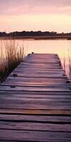 A wooden dock leads to the water at sunset photo