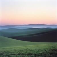 A green field with hills in the distance at sunset photo