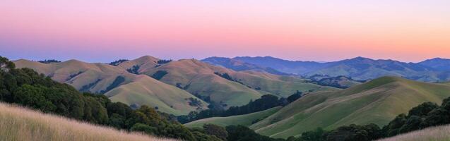 A view of the mountains at sunset with grass and trees photo