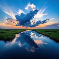 A beautiful sunset over a marshy area with clouds reflected in the water photo