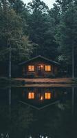 A cabin in the woods with a reflection of the house in the water photo