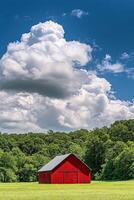 A red barn sits in a green field with trees and clouds photo