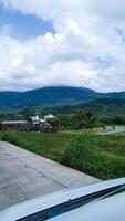 Green scenery in the mountainous area with clouds covering the mountain peaks photo