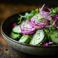 Fresh sliced cucumber salad with red onion and dill in a bowl on a wooden background. Macro close up shoot, selective focus. Dark rustic background. photo