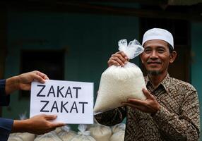A man holding a bag of rice with a sign that says zakat katat photo