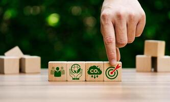 Hand Arranging Wooden Blocks Representing Sustainability Goals, Carbon Reduction, Environmental Responsibility, and Target Achievement in Green Business Strategy photo