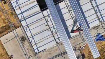 Aerial view of construction workers installing roofing panels on a building, surrounded by tools and materials, showcasing teamwork, precision, and the construction process in progress photo
