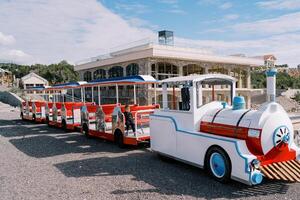 Little girl sits in the carriage of a colorful train on the playground photo