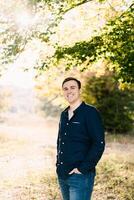 Smiling man standing on the lawn under a tree photo
