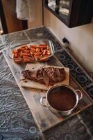 Sliced roast beef on a cutting board stands next to a baked sweet potato in a glass dish on the table photo