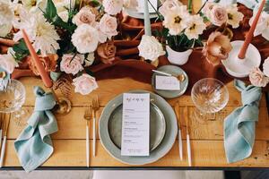Invitation on a saucer lies next to a festive menu on a plate on a table with bouquets of flowers photo