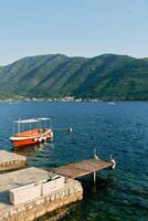Red excursion boat moored at the pier against the backdrop of mountains photo