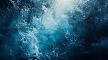 Aerial view of the ocean showcasing turbulent surface with shades of blue and white textured waves and splashing patterns photo