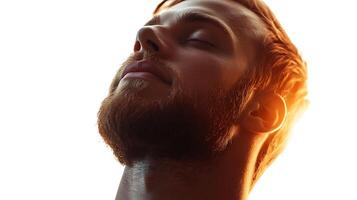 A close-up of a serene man with a beard eyes closed basking in the golden light capturing a moment of peaceful reflection photo
