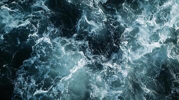 Aerial view of a turbulent sea with a mix of deep blue and lighter shades creating a dynamic foamy pattern photo