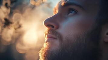 A close-up of a man with a beard looking up illuminated by soft golden light and with a bokeh background Contemplation photo