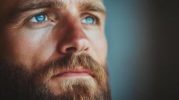 Focused gaze of a man with intense blue eyes and ginger beard against a blurred background Close-up shot photo