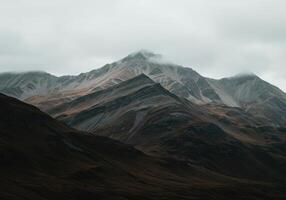 Layered mountains ascend into a cloudy sky, creating a dramatic and serene landscape view. photo