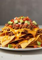 A delicious pile of loaded nachos features cheese, ground beef, and a fresh avocado and tomato salsa. photo