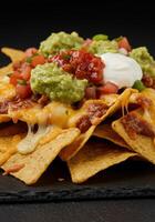 A tempting close-up of fully loaded nachos with melted cheese, guacamole, and fresh salsa. photo