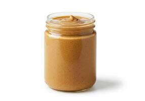An open glass jar of smooth peanut butter ready to be enjoyed on a sandwich or with a spoon. photo