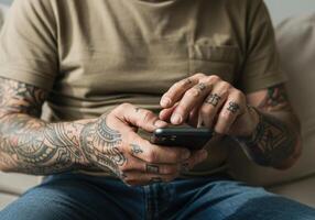 A tattooed man is casually using his smartphone, showing the connection between technology and personal expression. photo