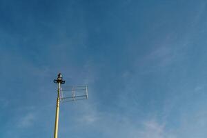 Antenna on a pole with searchlights and a signal lantern on the top against the sky photo
