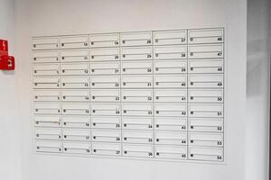 Row of white mailboxes with letters sticking out from one slot. Indoor hallway mailbox system in a residential building. Mail delivery and correspondence concept. photo