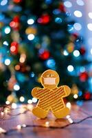 Cookie in the shape of a man in a protective mask on the table against the backdrop of sparkling garlands photo