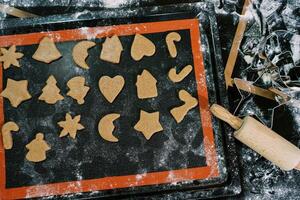 Die-cut Christmas cookies of various shapes lie on a tray on the table. Cropped photo