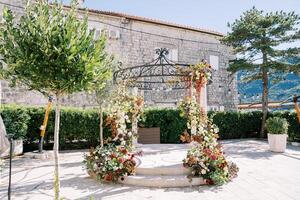 Alcove with columns decorated with flowers in the courtyard of an ancient stone house photo