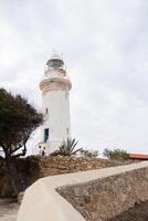 White lighthouse s under a partly cloudy sky flanked by trees photo