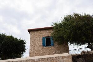 View of house with orange tile roofs,blue exterior window shutter surrounded by olive trees in Cyprus photo
