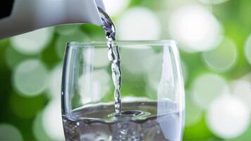 Refreshing Water Pouring into a Clear Glass with Blurred Green Background photo