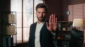 Confident serious Caucasian man male guy businessman business leader boss company CEO in office looking at camera put hand in front stop gesture enough refuse limit keep distance deny forbid protect video