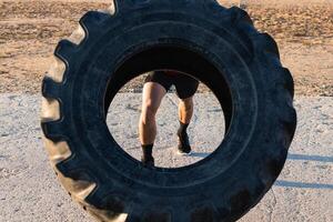 Anonymous strong man doing tire flip exercise photo