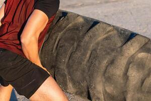 Anonymous strong man doing tire flip exercise photo
